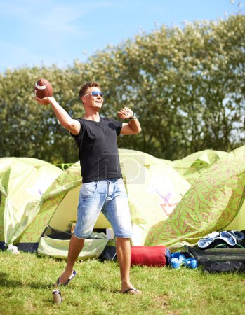 Téléchargez les photos : N'importe qui pour une partie de pêche. un jeune homme debout devant sa tente prêt à lancer un ballon de football - en image libre de droit