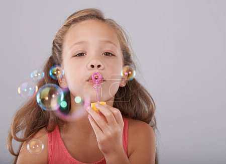 Téléchargez les photos : Amusant avec les bulles. Plan studio d'une jolie petite fille soufflant des bulles - en image libre de droit