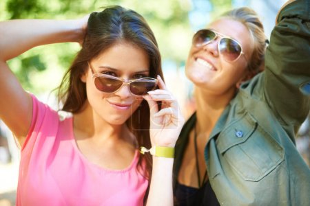 Téléchargez les photos : Style sans soucis. Deux jeunes femmes debout dehors portant des lunettes de soleil - en image libre de droit