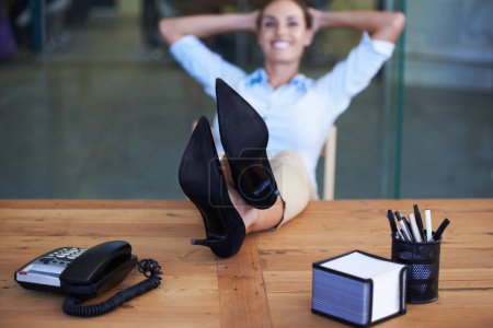 Photo for Heres to a job well done. A businesswoman sitting back with her feet on her desk - Royalty Free Image