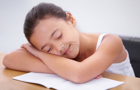 Photo for Taking a rest from her studies. A little girl sleeping in her desk in the classroom - Royalty Free Image