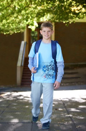 Photo for Making his way to class. A smiling young boy wearing a backpack on his way to school - Royalty Free Image