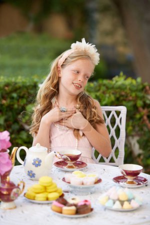 Photo for Hosting a pretend tea party. A cute little girl having a tea party outside - Royalty Free Image