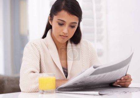 Foto de Revisando los detalles... una joven leyendo un periódico por la mañana - Imagen libre de derechos