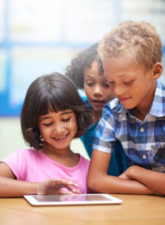 Foto de Integración de la tecnología en su aula. niños de primaria que usan una tableta digital mientras están sentados en clase - Imagen libre de derechos