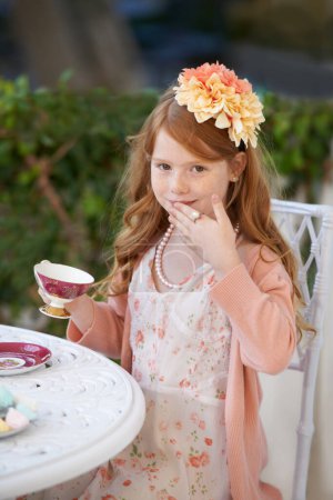 Foto de Siendo una dama... una niña pelirroja vestida y haciendo una fiesta de té en su jardín - Imagen libre de derechos