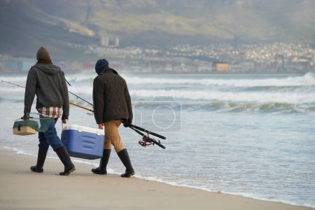 Foto de Pesca de agua salada Hombre vs Mar. Tiro de longitud completa de dos hombres jóvenes que pescan en el océano por la mañana temprano - Imagen libre de derechos