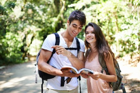 Téléchargez les photos : Où allons-nous ensuite ? un jeune couple debout avec un guide lors d'une randonnée en forêt - en image libre de droit