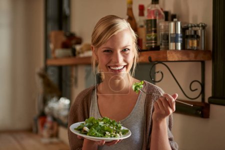 Photo for It always tastes better when you make it yourself...Portrait of an attractive young woman eating a salad in her kitchen - Royalty Free Image