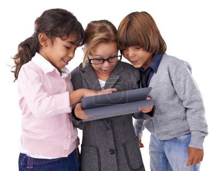 Foto de Explorando nuevos mundos. Foto de estudio de tres niños de pie y trabajando en una tableta - Imagen libre de derechos