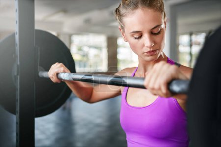 Photo for Strong is the new beautiful. a young woman working out with weights at the gym - Royalty Free Image