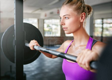 Foto de No uses máquinas, conviértete en una. una joven haciendo ejercicio con pesas en el gimnasio - Imagen libre de derechos