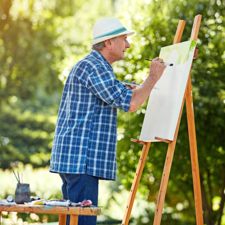 Téléchargez les photos : Mettre de la passion dans chaque peinture. un homme âgé peignant dans le parc - en image libre de droit