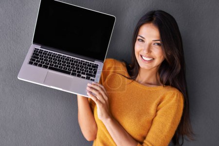 Photo for Tech-savvy beauty. Portrait of an attractive young woman holding up a laptop with a blank screen - Royalty Free Image