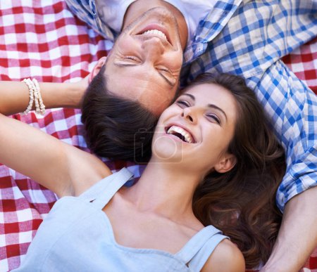Foto de Compartiendo un picnic romántico. Una feliz pareja joven disfrutando de un picnic bajo el sol de verano - Imagen libre de derechos