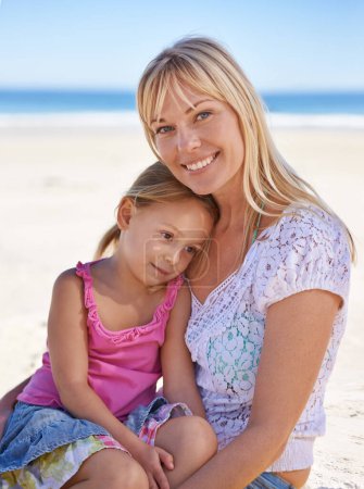 Téléchargez les photos : Des moments précieux sur la plage. Portrait d'une mère assise avec sa fille sur la plage - en image libre de droit