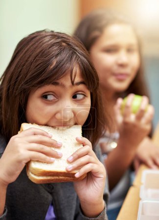 Téléchargez les photos : Manger rapidement pour battre la cloche. jeunes écoliers déjeunant à l'école - en image libre de droit
