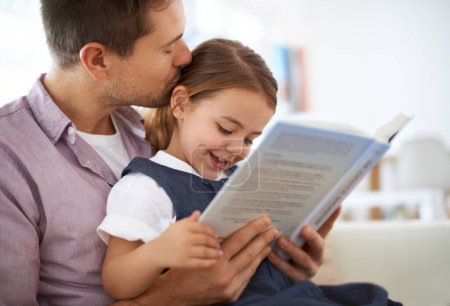Foto de Ella es la princesa en mi historia. un padre joven leyendo un libro con su hija - Imagen libre de derechos