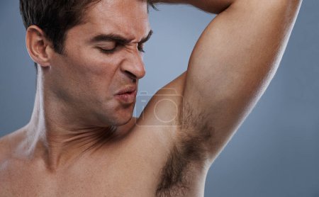 Photo for Not so fresh today...a handsome young man grimacing while smelling his armpit - Royalty Free Image