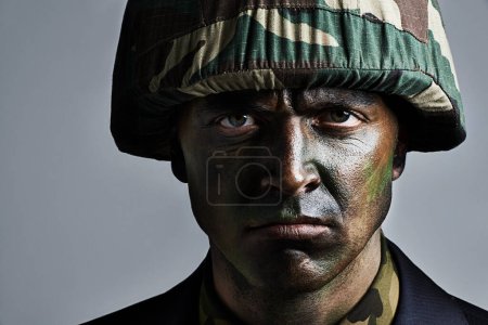 Photo for Ready for war. A serious military man with his face camouflaged - Royalty Free Image