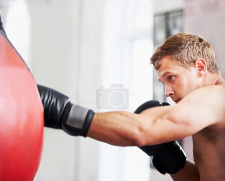 Strength and focus. A young boxer practicing with a punching ball