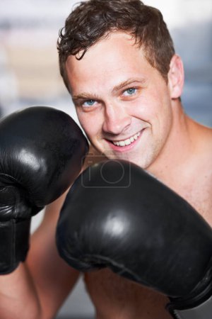 Photo for Gloves up. A young handsome boxer smiling at you with his gloves up - Royalty Free Image