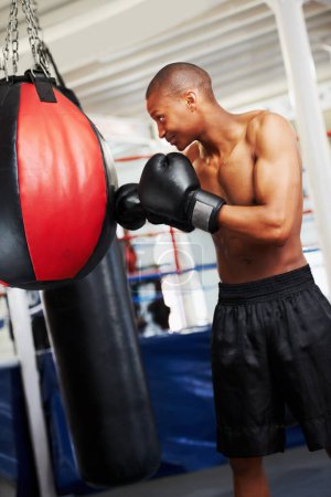 Téléchargez les photos : Mettre les heures difficiles dedans. Un boxeur afro-américain pratiquant avec un ballon de boxe - en image libre de droit