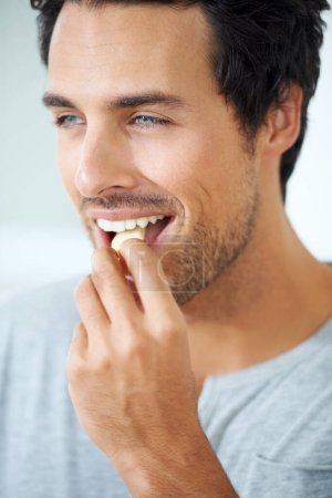 Gâteries savoureuses. Profil d'un magnifique jeune homme souriant qui mange une tranche de pomme