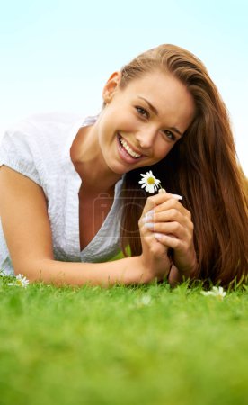 Téléchargez les photos : Portrait, heureux et femme avec marguerite sur l'herbe, couché sur le terrain et profiter du printemps en vacances en plein air. Sourire, plante de fleur et la beauté de la personne féminine relaxant, maquette et avoir du plaisir dans la nature - en image libre de droit