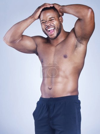 Foto de El trabajo duro hace un cuerpo duro. Estudio de un joven guapo posando sobre un fondo gris - Imagen libre de derechos