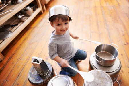 Photo for Portrait, fun and boy child playing drums on pans on a floor, happy and enjoying music. Face, creative and kid with pots for musical entertainment, silly and carefree in a kitchen on the weekend. - Royalty Free Image