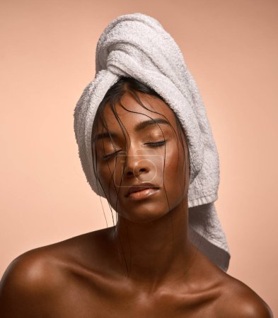 Photo for Im the wine stain on your shirt sleeve. a beautiful young woman with her hair wrapped in a towel against brown background - Royalty Free Image