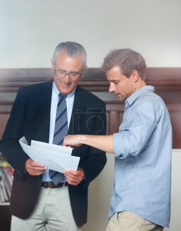 Photo for The best financial advisor in the business. Through-the-window shot of a young man looking over documents with his financial advisor - Royalty Free Image
