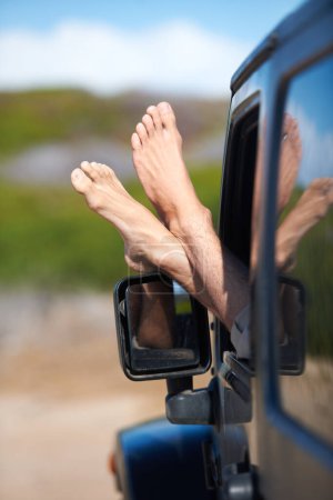 Die Füße hochlegen. Mann entspannt sich im Auto mit den Füßen aus dem Fenster