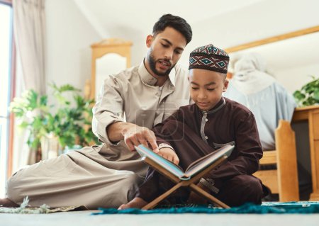 Photo for Education is an admirable thing. a young muslim man and his son reading in the lounge at home - Royalty Free Image