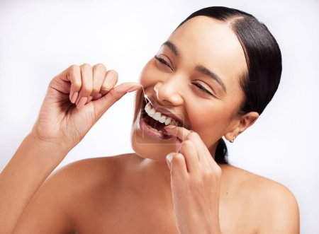 Foto de Dar pasos hacia una buena higiene bucal. Foto de estudio de una hermosa joven que usa hilo dental sobre un fondo blanco - Imagen libre de derechos