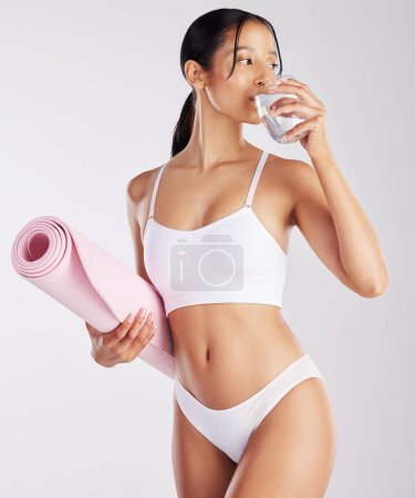 Photo for I drink water, exercise and eat healthy. a fit young woman holding a glass of water and a yoga mat - Royalty Free Image