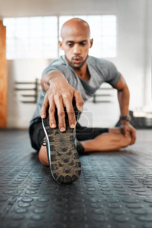 Photo for Breathe through this exercise. a young man stretching his legs before a workout - Royalty Free Image