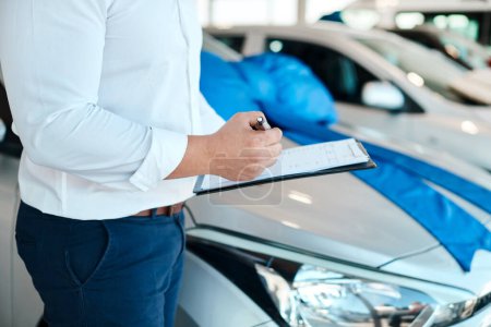 Photo for Always make sure contracts are in order. a car salesman writing on a clipboard - Royalty Free Image