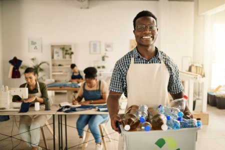 Photo for African american designer holding a recycling bin. Businessman holding a bucket of recycled plastic bottles. Young tailor holding a recycling bin. Smiling designer recycling plastic bottles. - Royalty Free Image