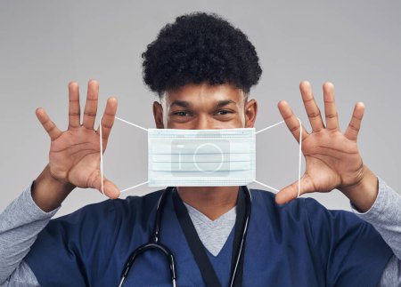 Photo for Lets make sure that everyone knows how important these are. a male nurse holding up a surgical mask while standing against a grey background - Royalty Free Image