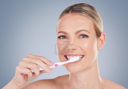 Foto de Haz brillar tus dientes. Retrato de estudio de una joven atractiva cepillándose los dientes sobre un fondo gris - Imagen libre de derechos