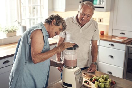 Téléchargez les photos : Tout est mélangé. un couple de personnes âgées faisant un smoothie dans la cuisine à la maison - en image libre de droit