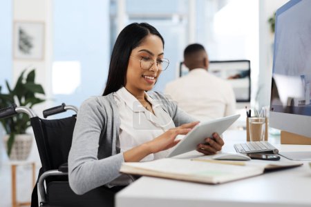 Foto de Comparando notas. una atractiva joven empresaria que trabaja en una tableta en su escritorio en la oficina - Imagen libre de derechos