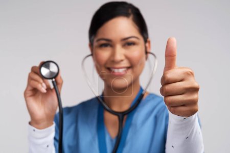 Photo for Forget being a princess, Im a doctor. Portrait of a young doctor showing thumbs up and holding a stethoscope against a white background - Royalty Free Image