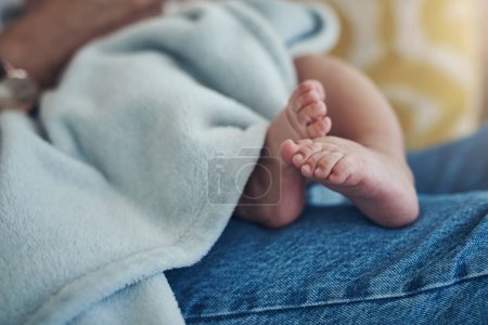 Téléchargez les photos : Tellement petits, si doux, adorables petits pieds de bébé. une femme méconnaissable se relaxant avec son bébé sur le canapé à la maison - en image libre de droit