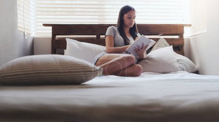 Journaling is a good way to clear your mind. a young woman sitting in bed while writing in her diary at home