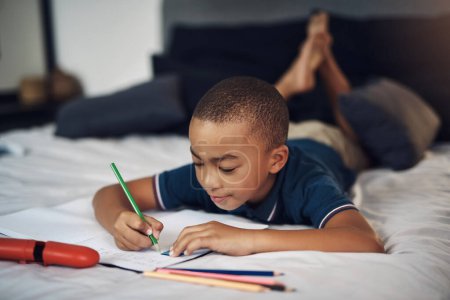 Foto de Mi profesor dijo que debería practicar mi alfabeto en casa. un niño joven usando lápices para colorear mientras escribe en casa - Imagen libre de derechos