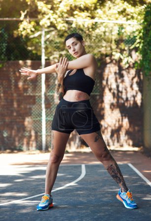 Photo for I warm up before every game. Full length portrait of an attractive young female athlete stretching while standing on the basketball court - Royalty Free Image