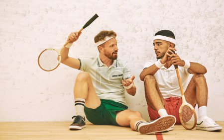 Téléchargez les photos : On se calme aussi fort qu'on joue. deux jeunes hommes bavardant après avoir joué à un jeu de squash - en image libre de droit